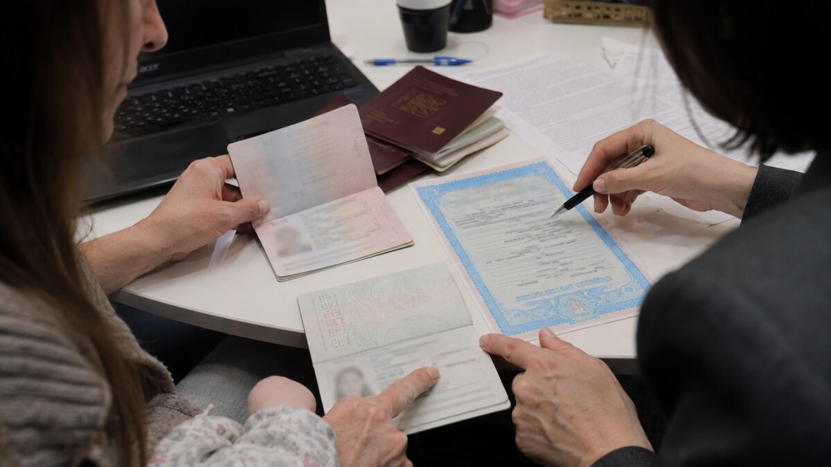 Перекладачка звіряє написання імен і прізвищ у свідоцтві про народження та закордонних паспортах